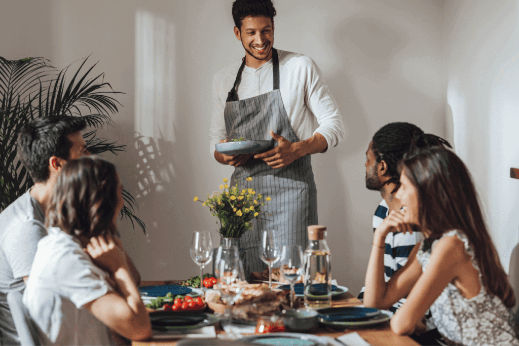 The host of a dinner party placing food on the table.