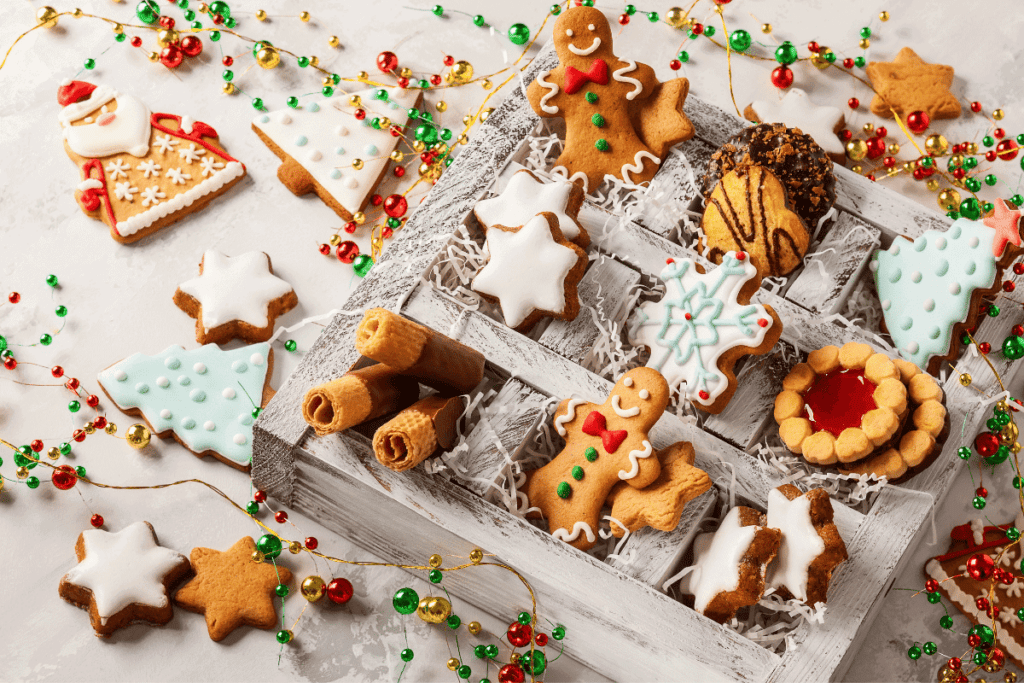 A box filled different Christmas cookies shaped like gingerbread, snowflakes, and Christmas trees.