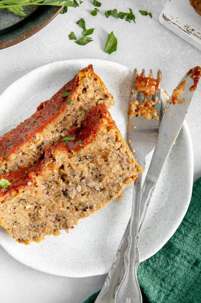 A messy fork and knife next to a couple of slices of lentil and quinoa meatloaf.
