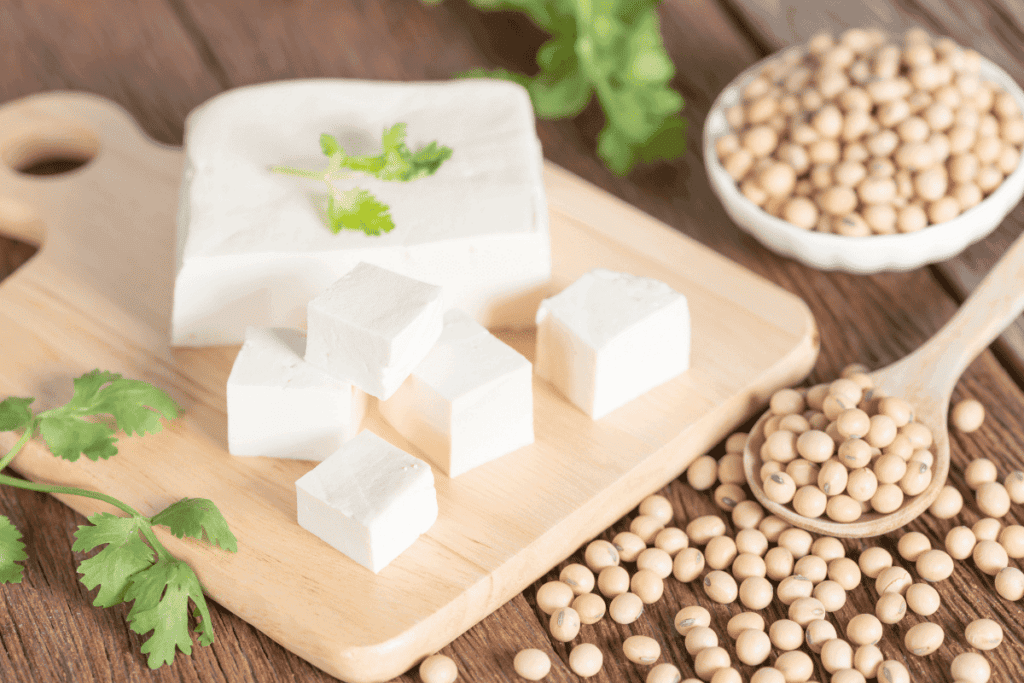 Sliced tofu on a cutting board next to soy beans.