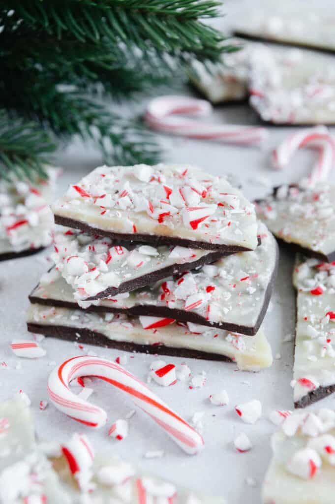 A stack of peppermint bark next to a candy cane.