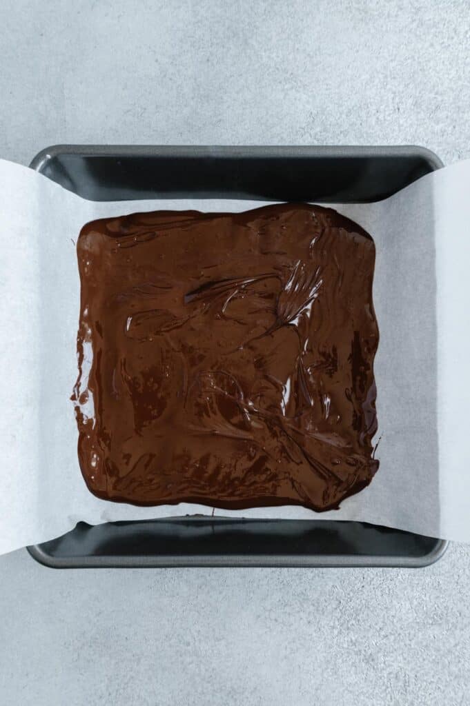 The first layer of dark chocolate in a baking pan.