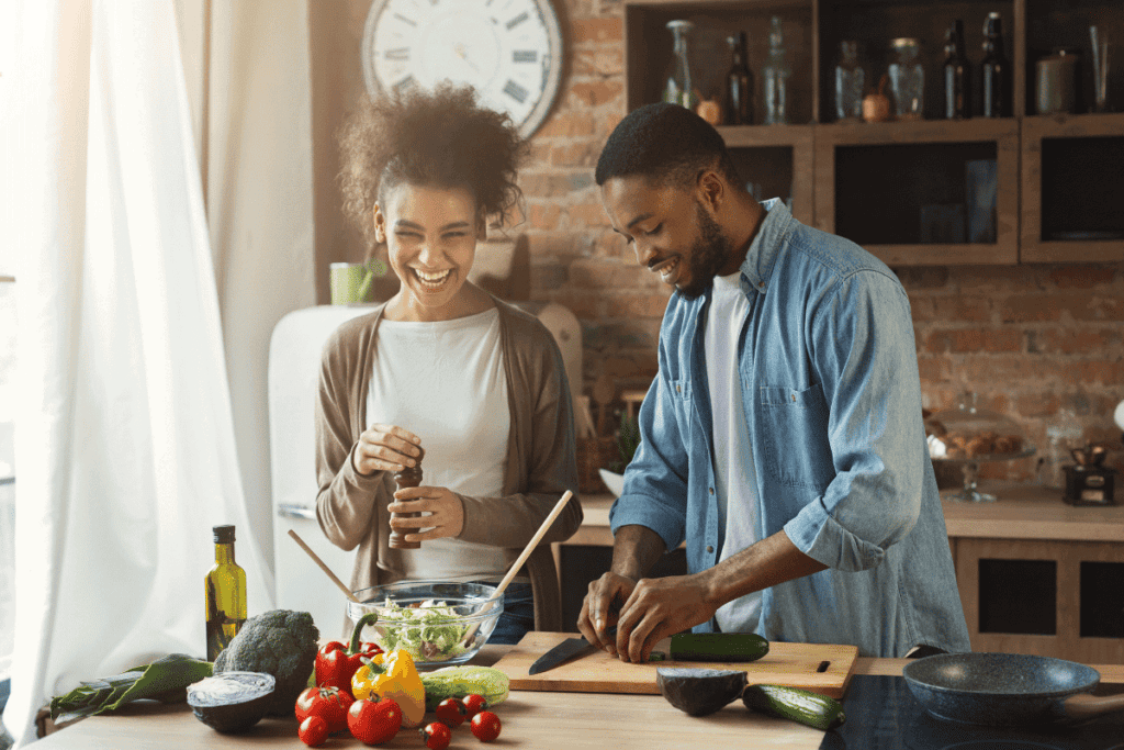 A couple laughing and cooking in the kitchen.