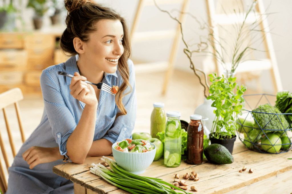 A girl sitting at a table eating a salad.