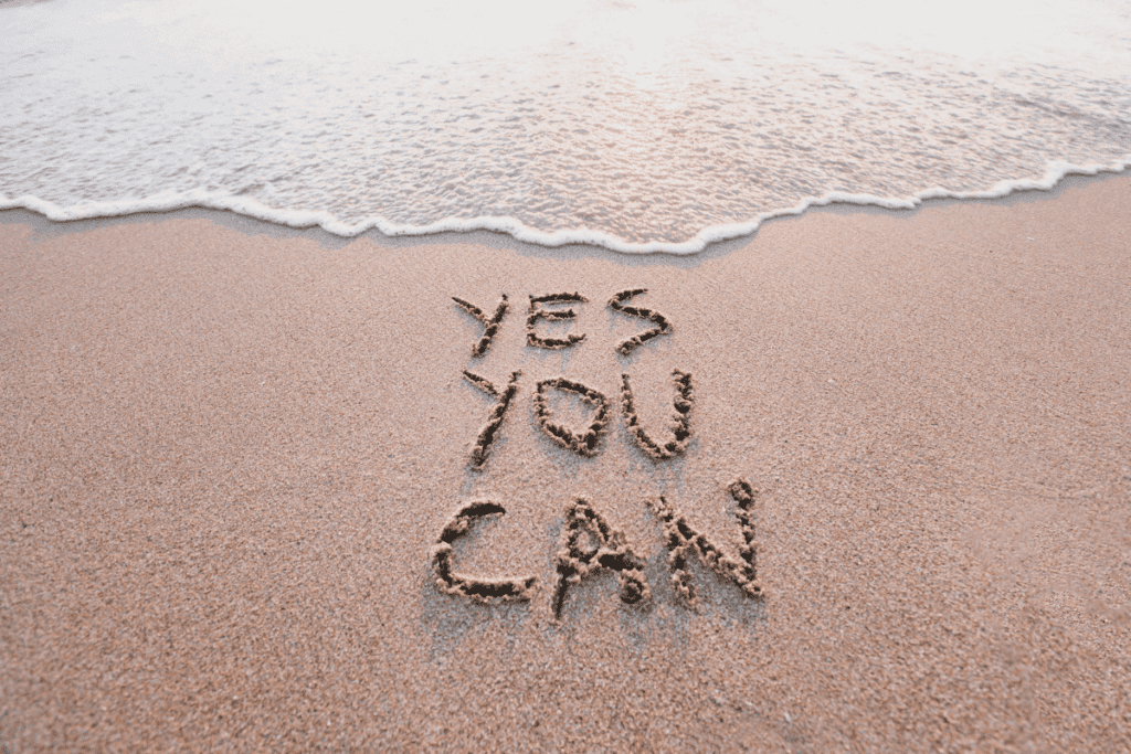 Sandy beach with the phrase "yes you can" in the sand.