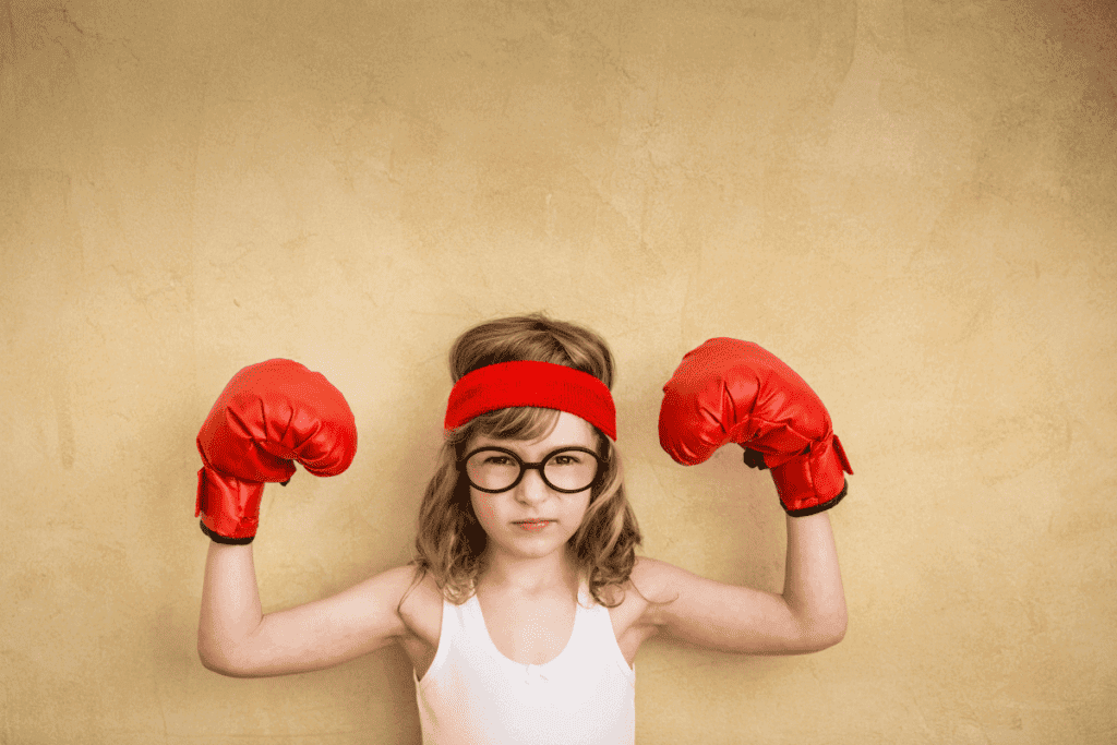 A little girl with boxing gloves on.