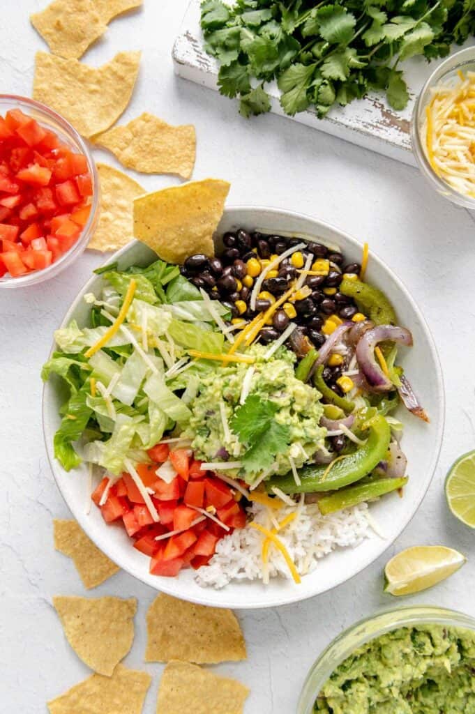 A vegan burrito bowl with chips surrounding it.