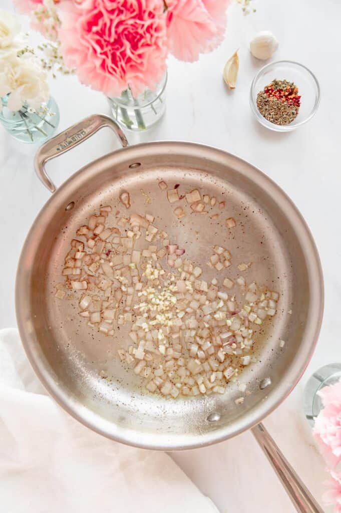 Shallots and garlic sautéing in a pan.