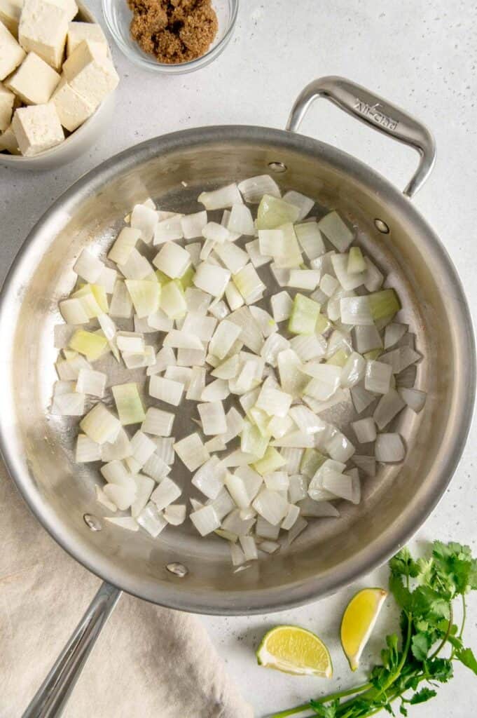 White onions sautéing in a pan.