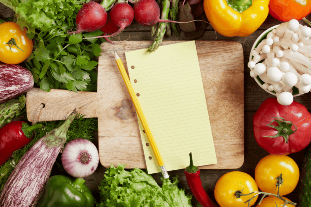 A grocery list surrounded by colorful vegetables.
