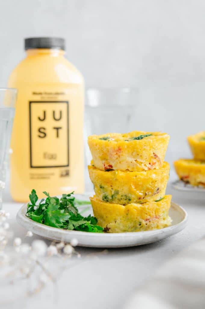 Egg bites stacked on top of one another with the Just Egg bottle in the background.