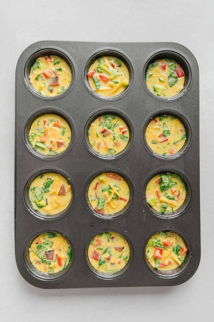 Uncooked egg bites in muffin tins.