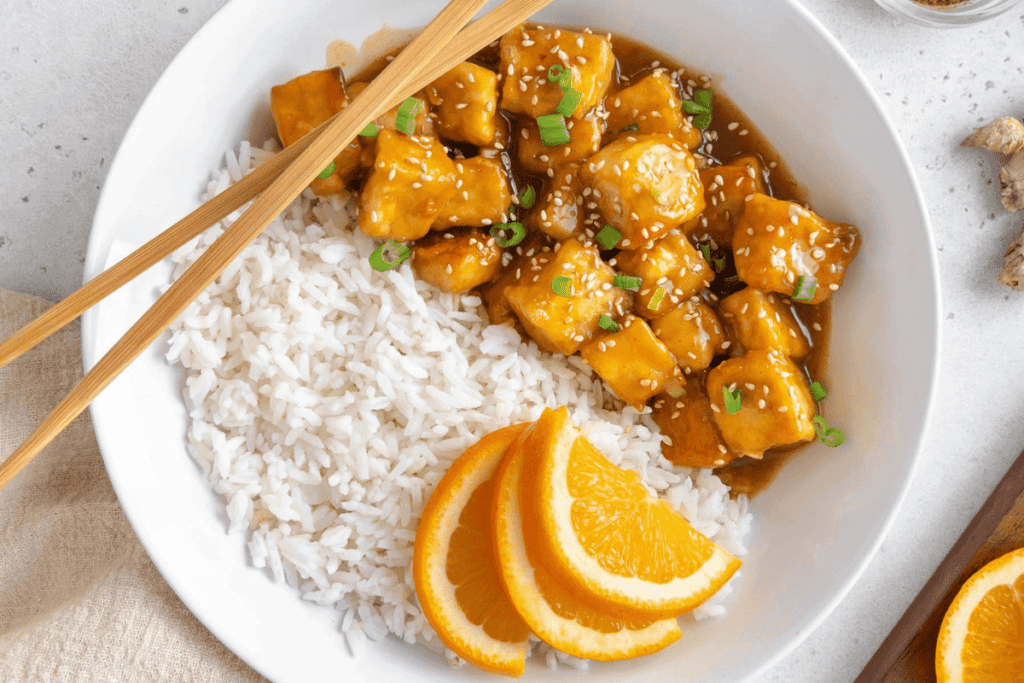 Vegan orange tofu in a bowl with white rice.