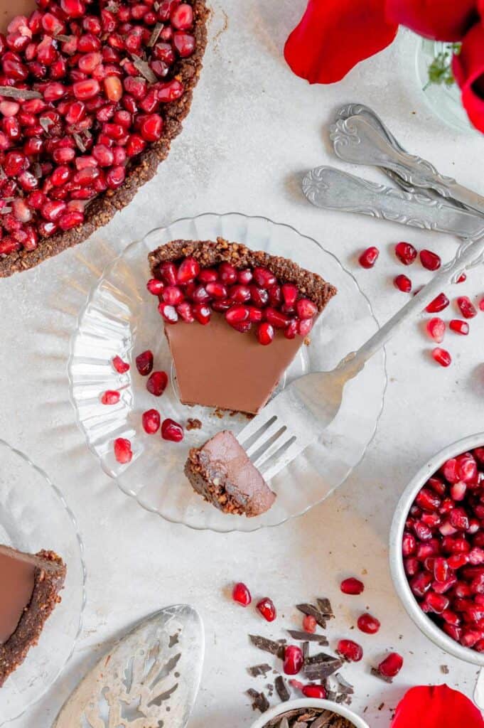 A pomegranate chocolate tart with a bite on a fork.