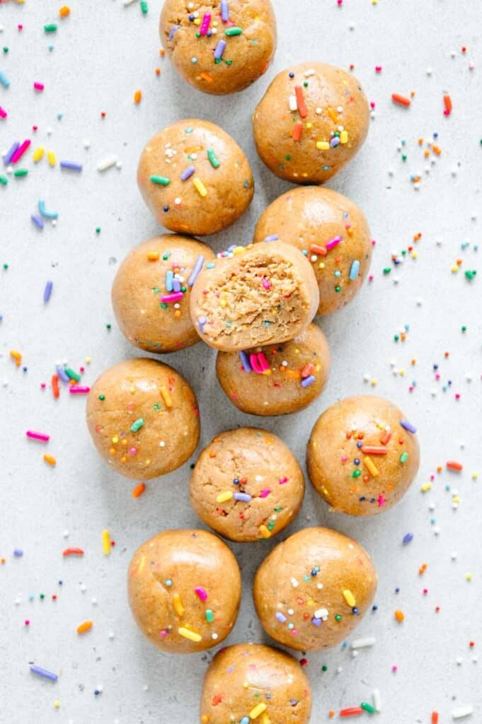 A bunch of funfetti cake bites with one that has a bite taken out of it.