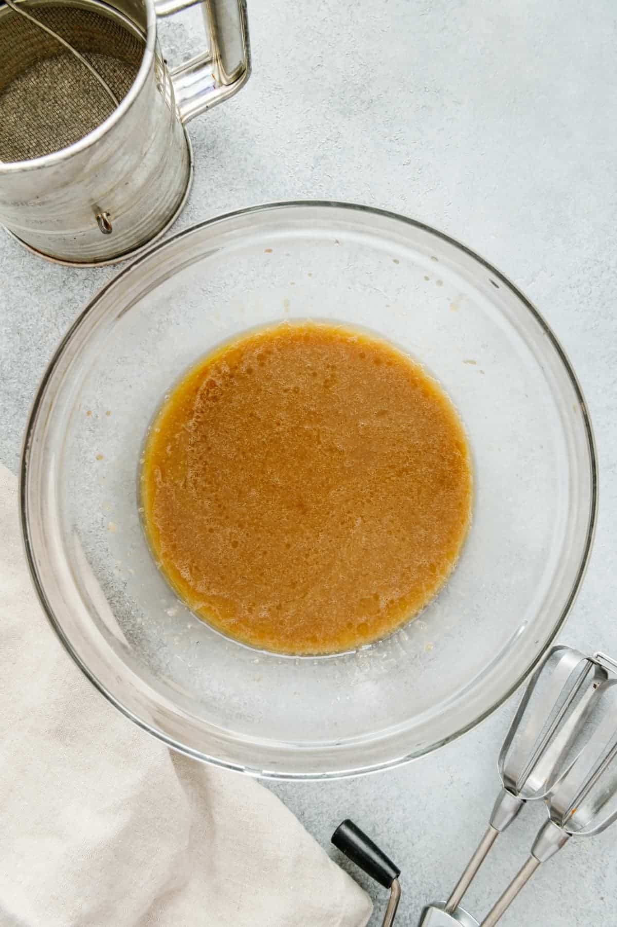 Wet ingredients added to mixing bowl with brown sugar and butter.