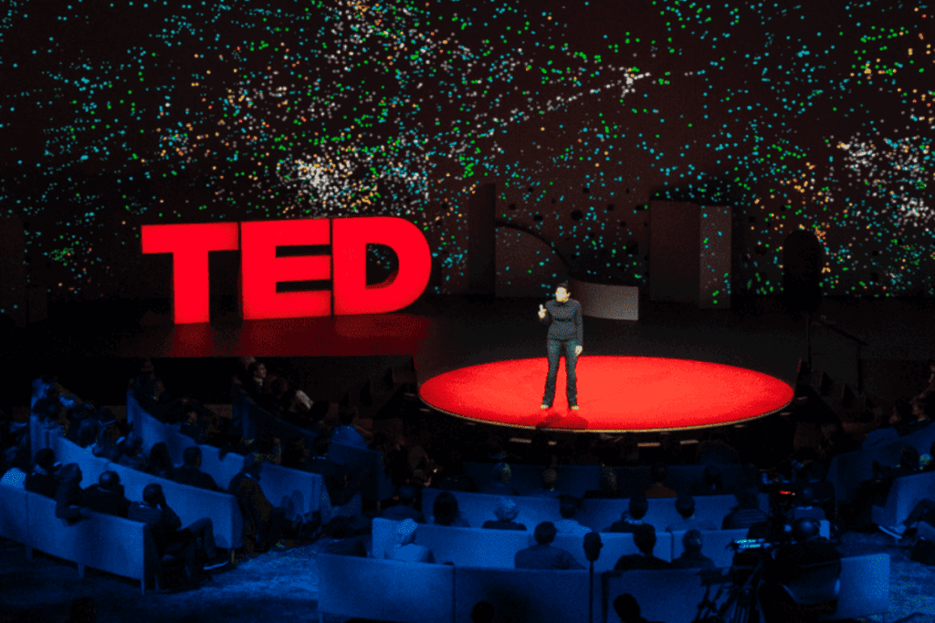 A TED talk stage with a speaker standing on it.
