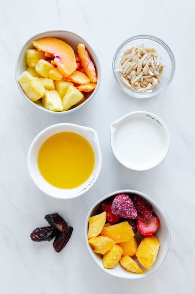 Ingredients to make a tropical smoothie in glass bowls.