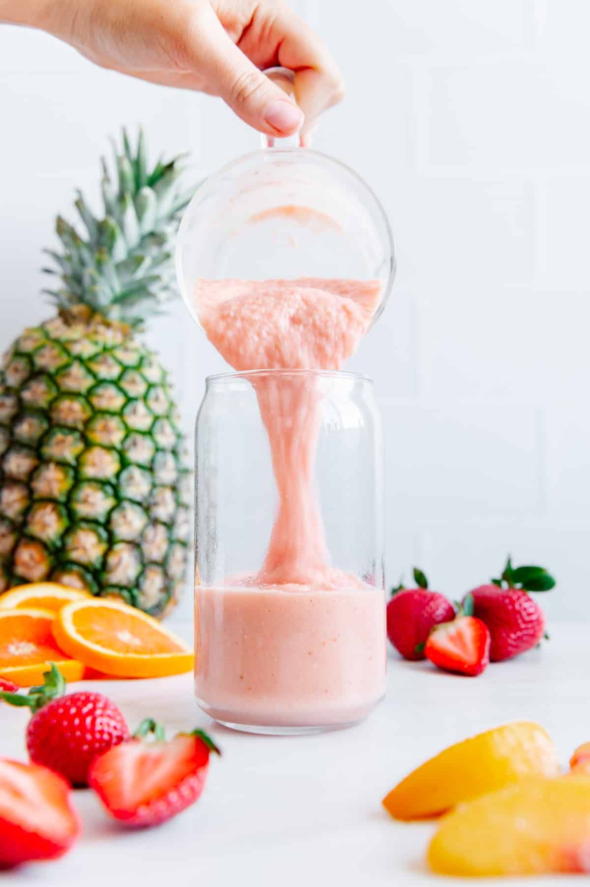 A vegan tropical smoothie being poured into a glass.