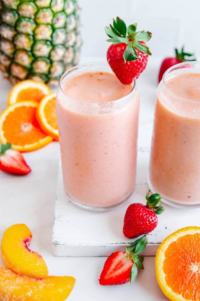 A fruit-filled tropical smoothie in two glasses.