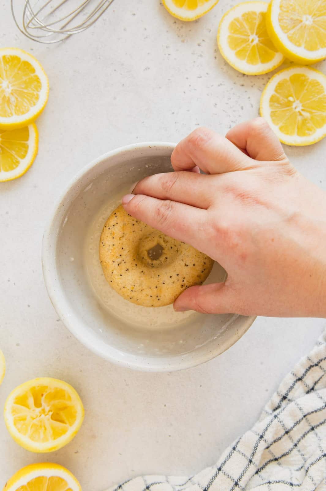 Lemon donut being dipped in an easy homemade glaze.