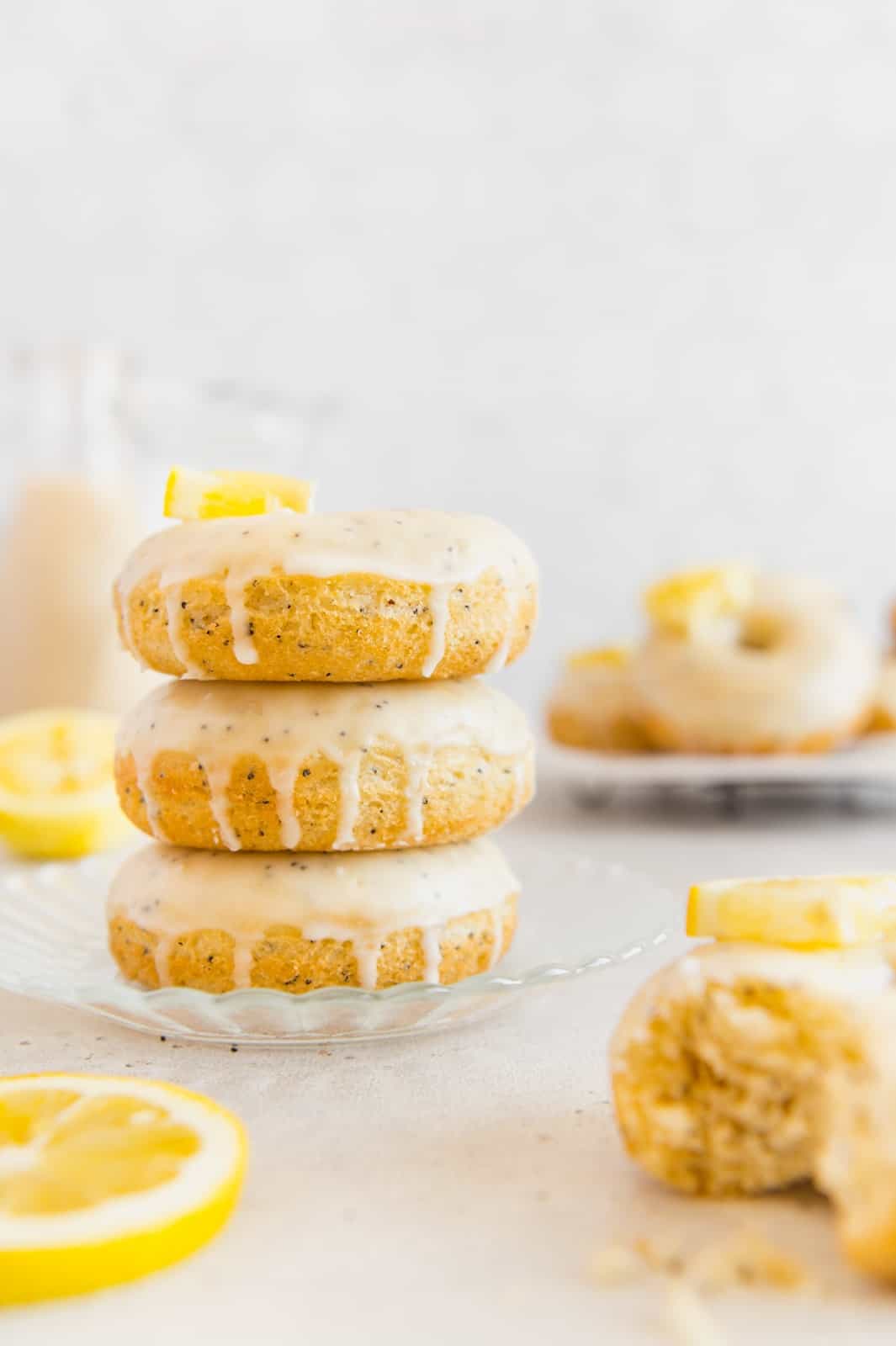 A stack of lemon glazed donuts on a scalloped glass plate.