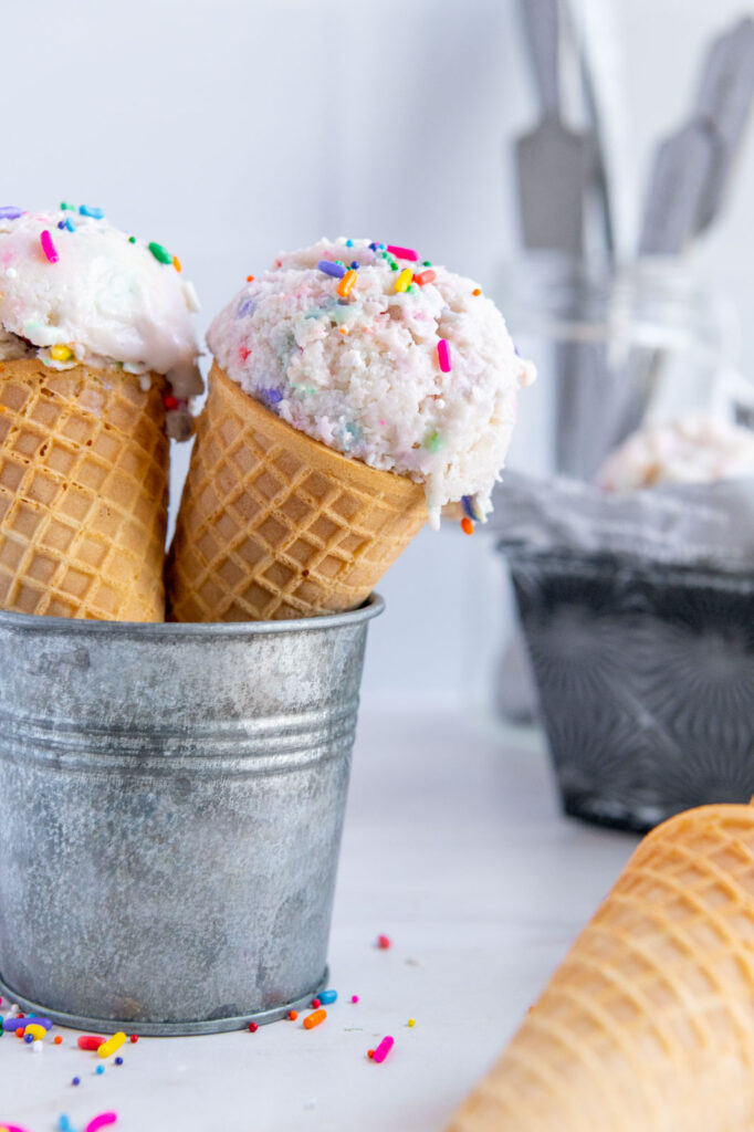 Two ice cream cones of vegan ice cream with sprinkles.
