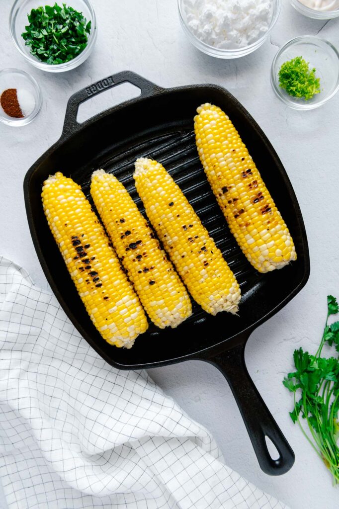 Corn on the cob grilling in a cast iron grill pan.
