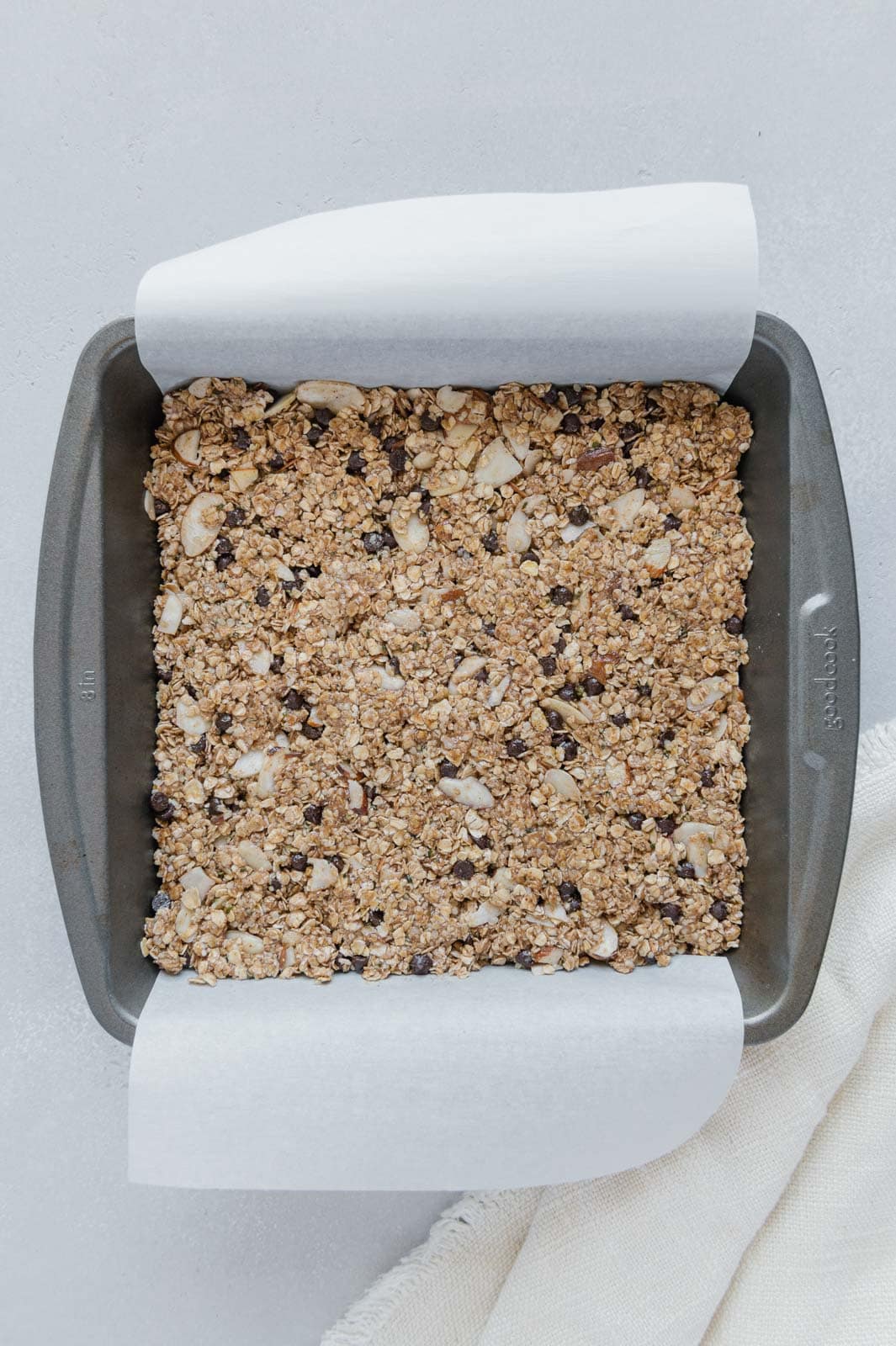 Pressed down granola bar mixture in an 8x8 baking pan ready for the refrigerator.
