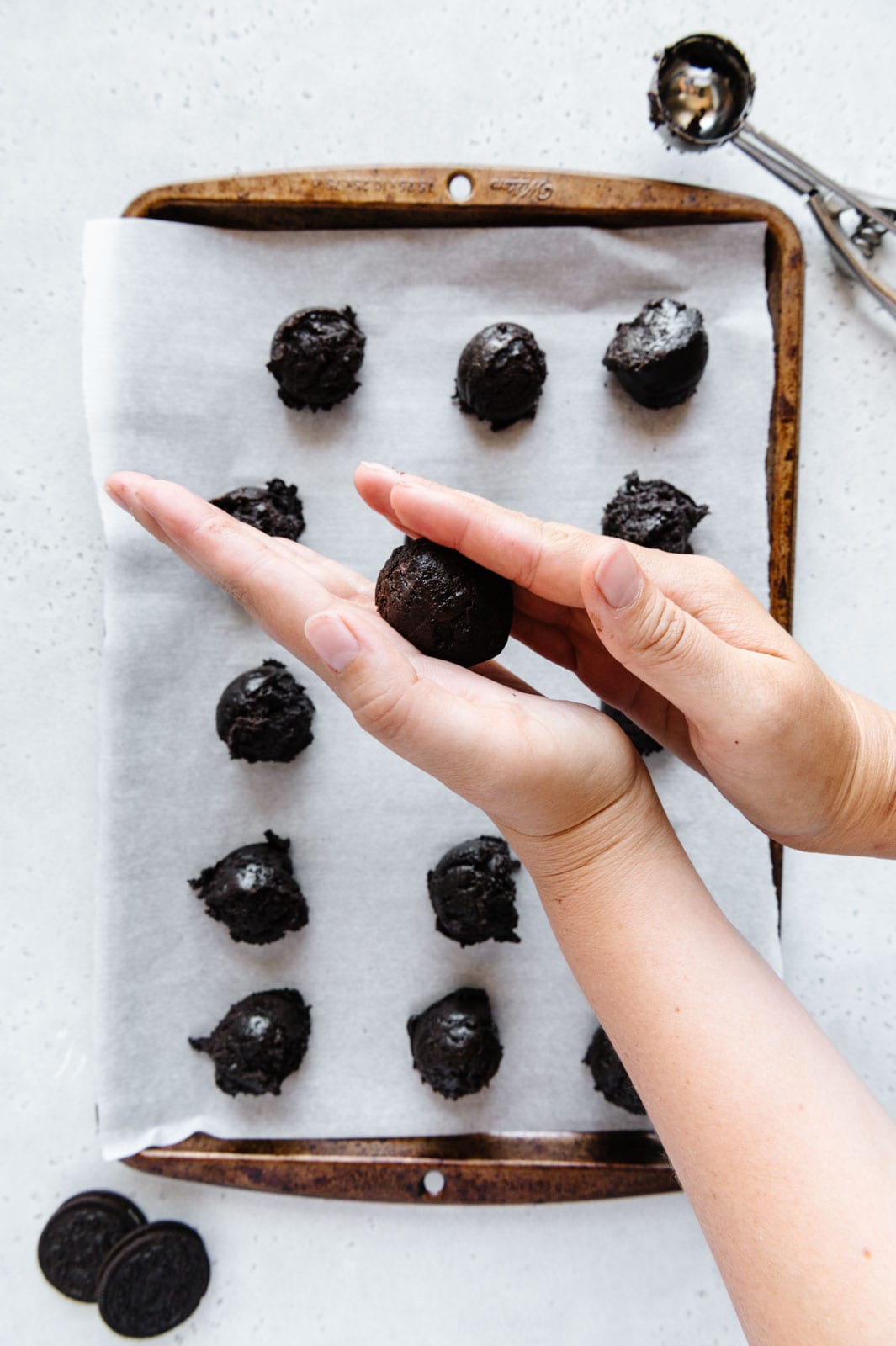 Hands rolling Oreo truffles into bite-sized balls.