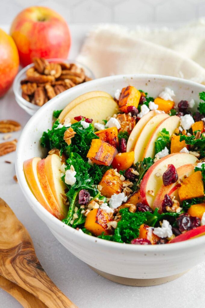 Upclose of a marinated kale salad with apples, cranberries, vegan feta, and butternut squash.
