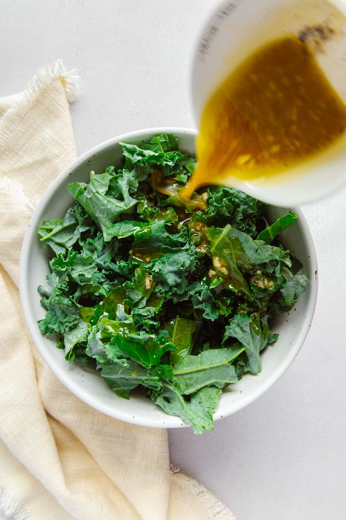 Chopped kale being drizzled with a maple apple cider dressing.