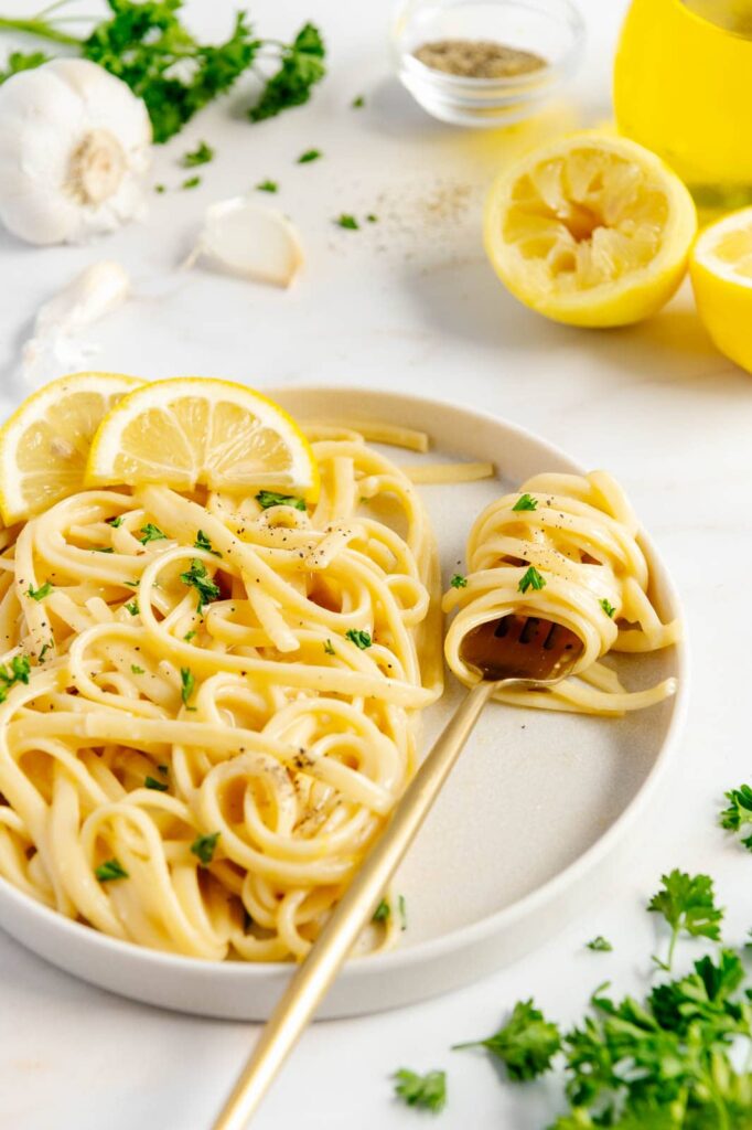 A plate with a fork swirled with pasta al limone.