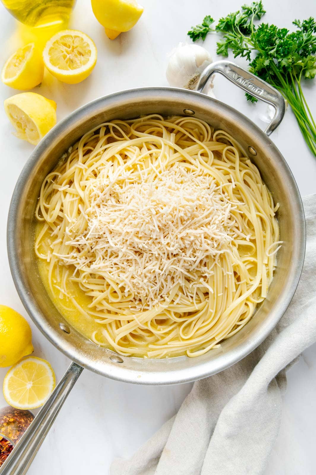 Vegan Parmesan cheese and linguine noodles added to saucepan.