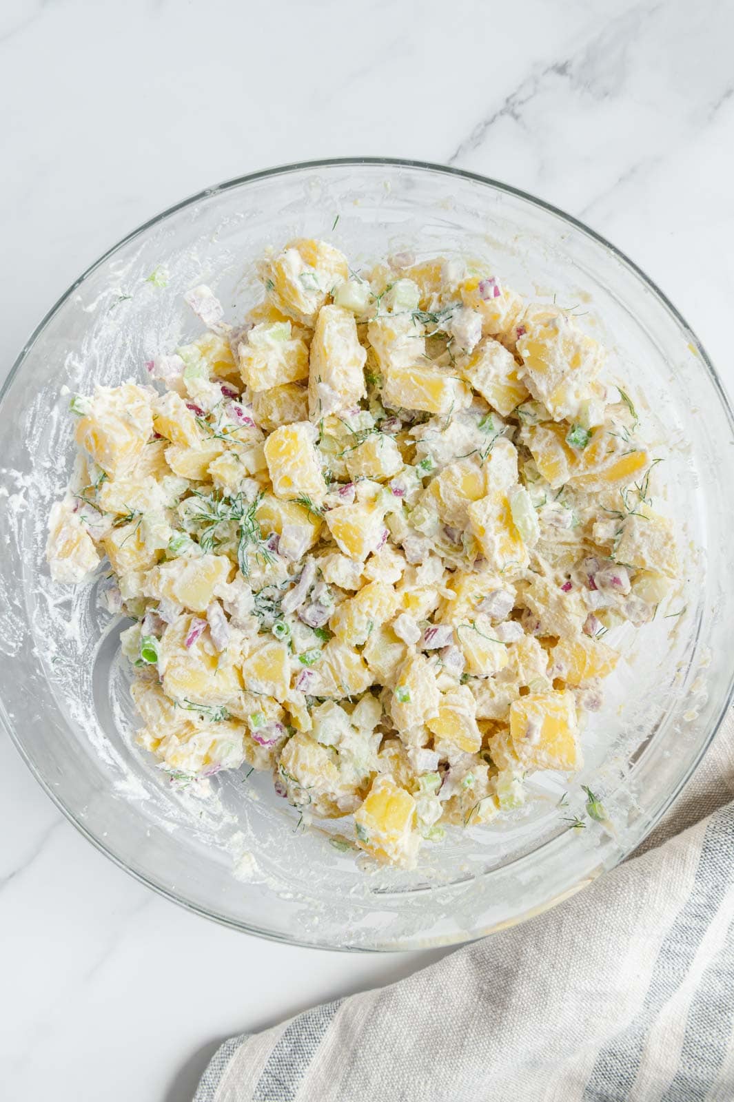 Creamy vegan potato salad mixed together in a mixing bowl.