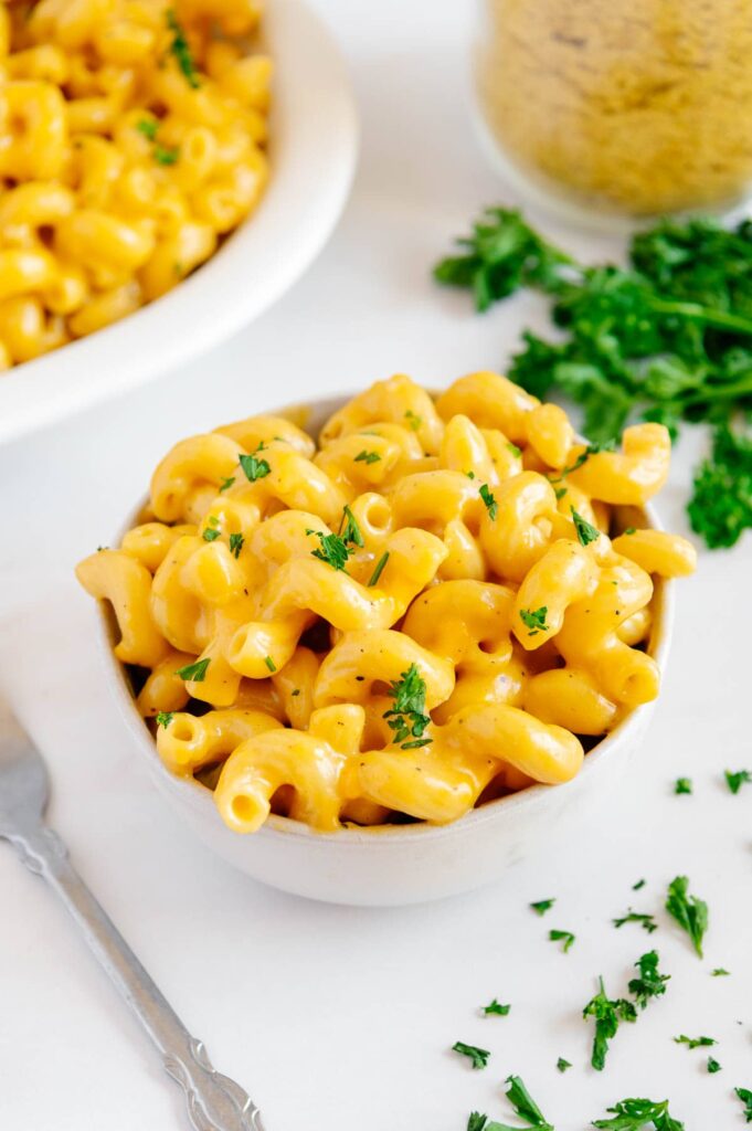 A bowl of vegan mac and cheese garnished with parsley.