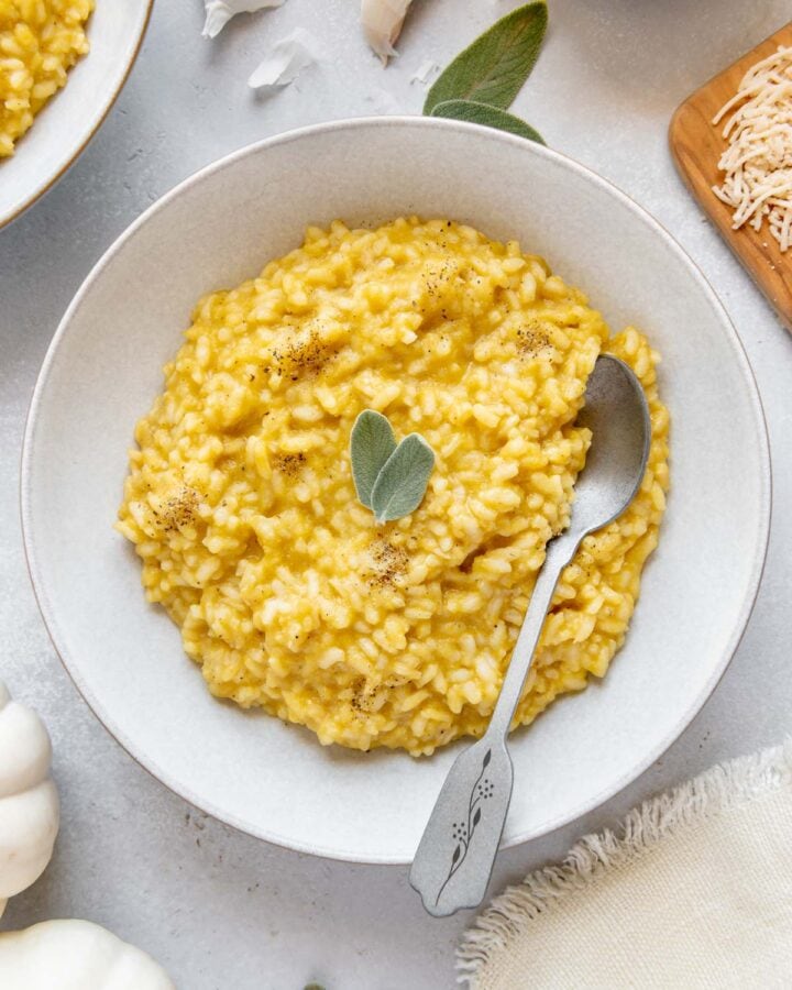 Pumpkin risotto in a serving bowl with a spoon.
