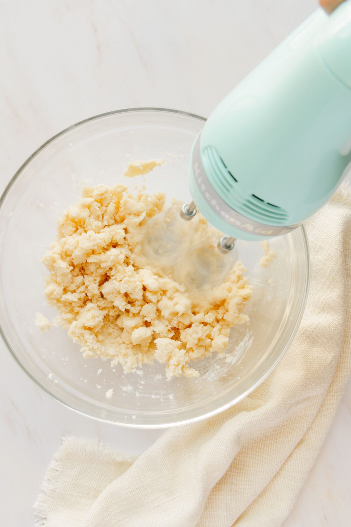 Vegan butter and sugar being whipped together with a hand mixer.