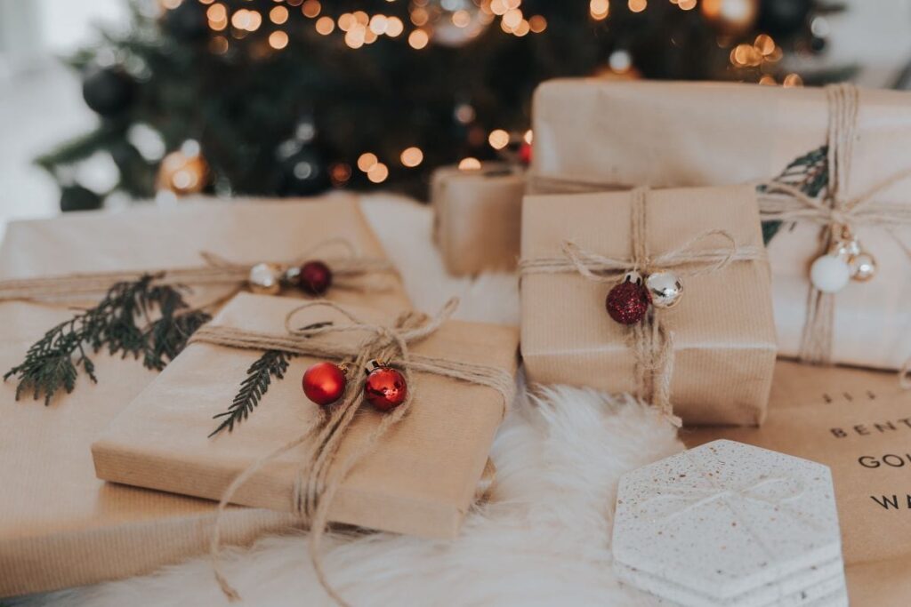 Brown wrapped presents in front of a Christmas tree.