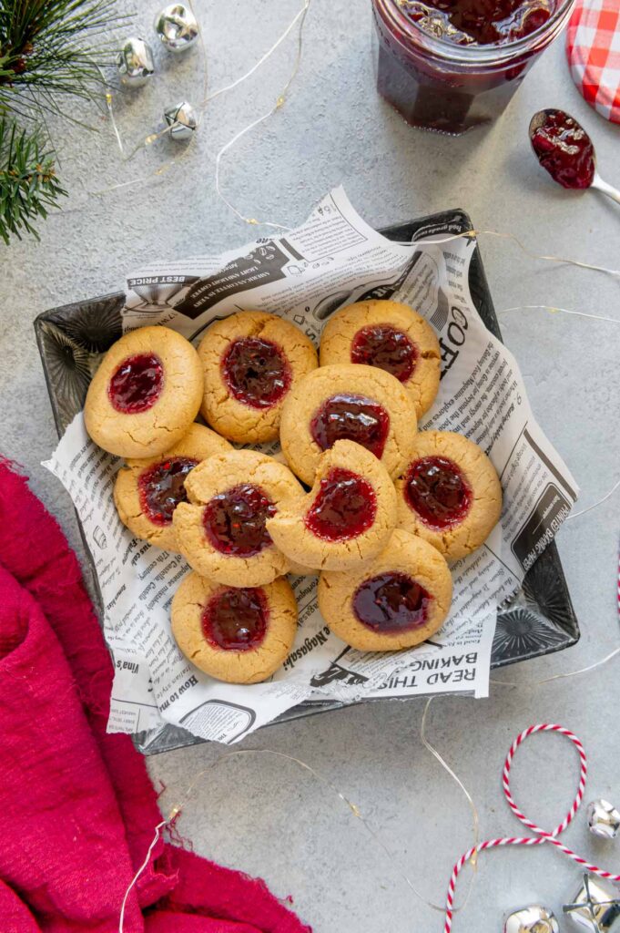 PB&J thumbprint cookies in a cookie tin with holiday decorations.
