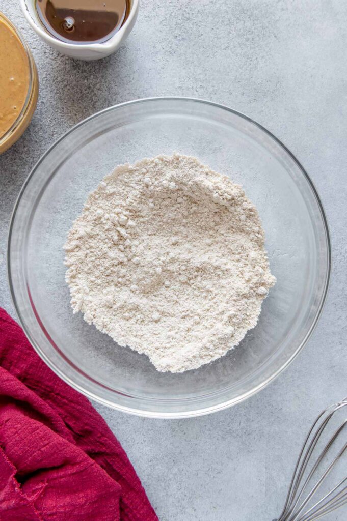 Oat flour and baking soda mixed in a mixing bowl.