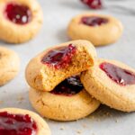 A vegan peanut butter and jelly thumbprint cookie with a bite taken out of it.