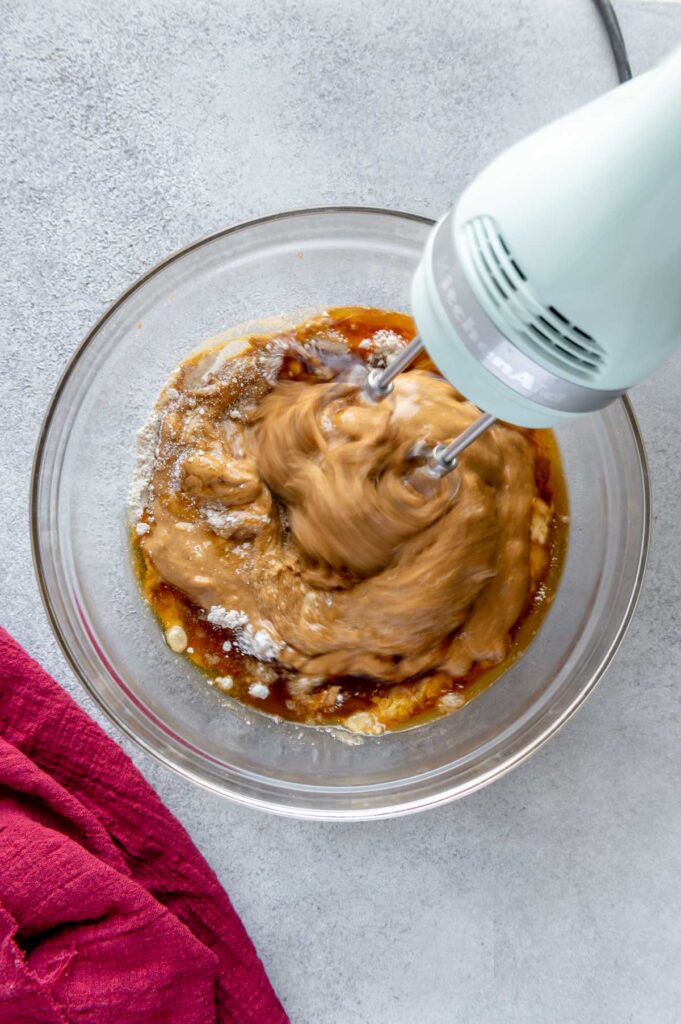 Peanut butter and jelly cookie batter being mixed with a hand mixer.