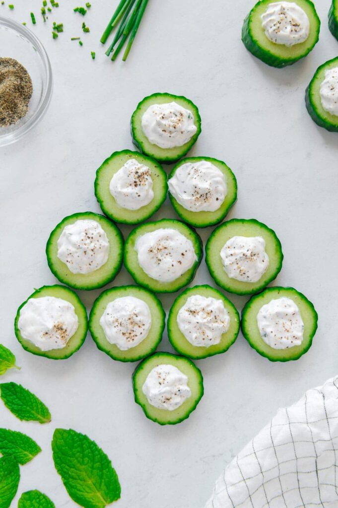 Cucumber bites arranged in the shape of a Christmas tree for a holiday party.