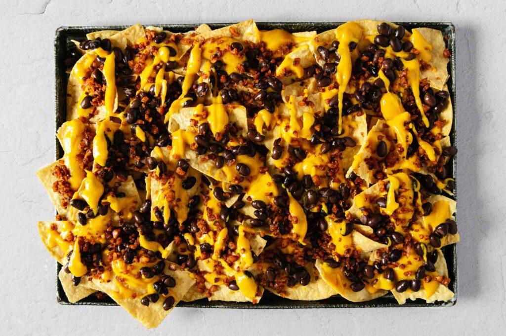 Sheet pan nachos with cheese, beans, and walnut taco meat on top.