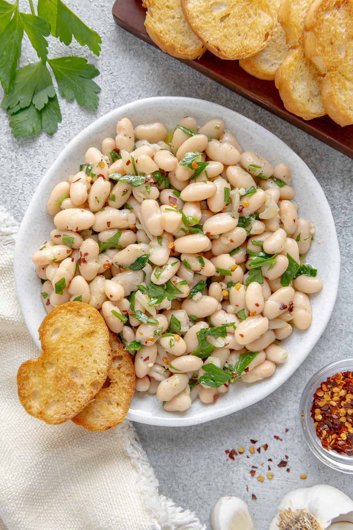 Tuscan bean salad on a serving plate with crunchy crostini.