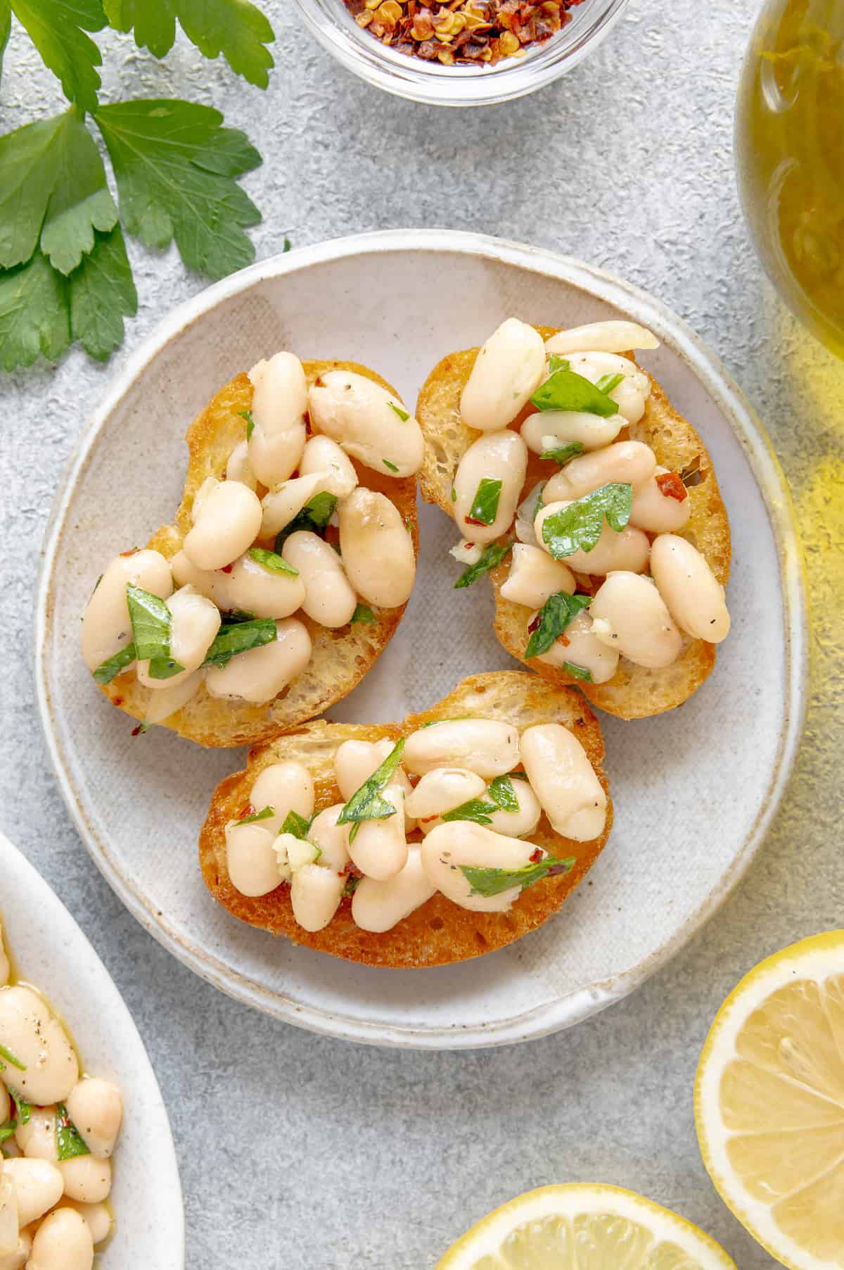 White bean dip spooned on crostinis on a plate.