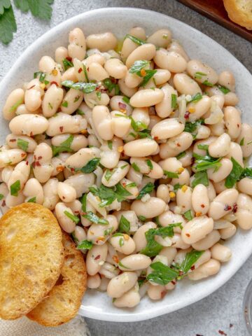 Tuscan bean salad on a serving plate with crunchy crostini.