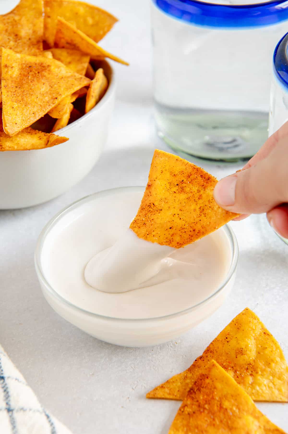 A homemade tortilla chip being dipped in sour cream.