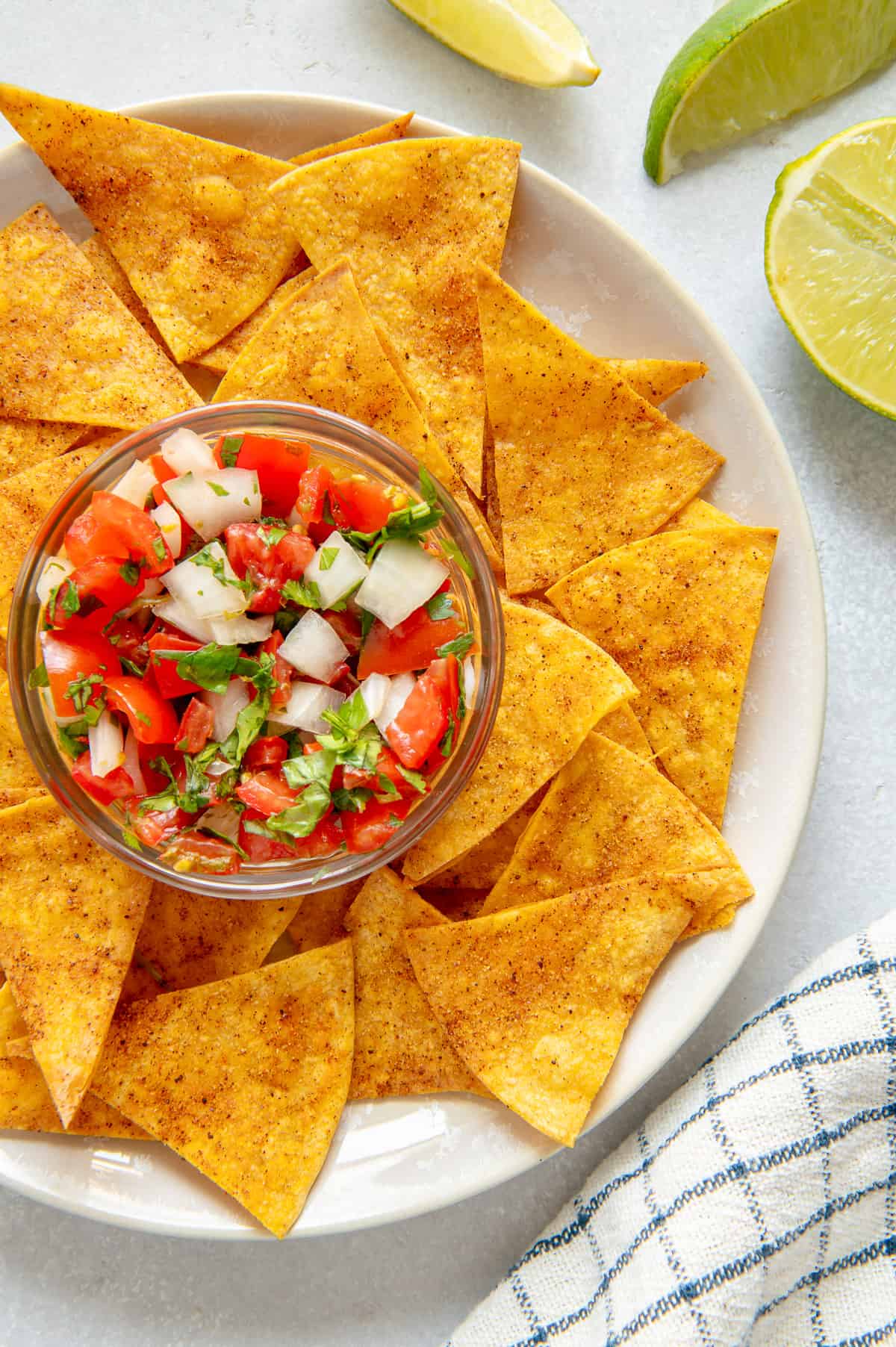 A plate of air fryer tortilla chips with a bowl of pico de gallo for dipping.